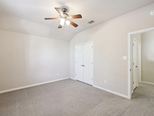 unfurnished bedroom featuring carpet flooring, a closet, vaulted ceiling, and ceiling fan