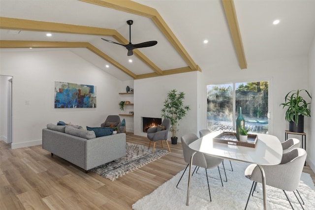 living room with beamed ceiling, light hardwood / wood-style floors, high vaulted ceiling, and ceiling fan