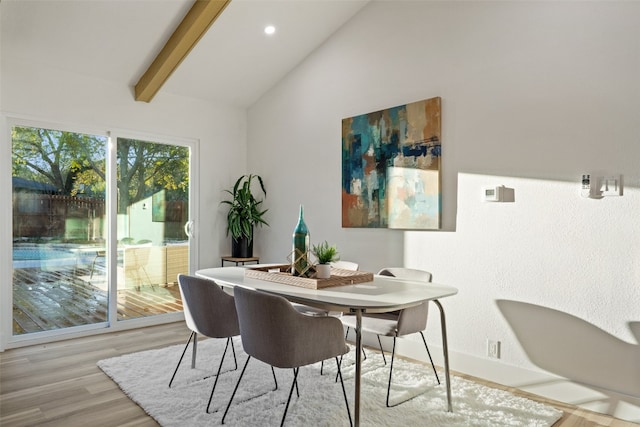 dining room with vaulted ceiling with beams and light hardwood / wood-style flooring