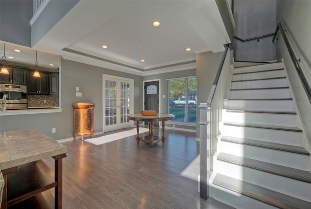 staircase featuring hardwood / wood-style floors, a raised ceiling, and crown molding