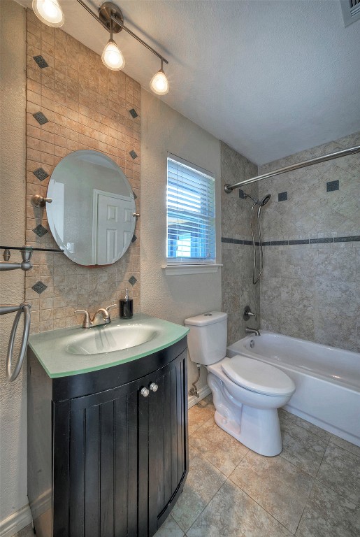 full bathroom with vanity, tile patterned floors, tiled shower / bath combo, toilet, and a textured ceiling