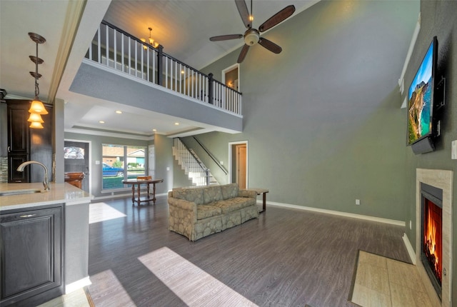 living room with a raised ceiling, sink, crown molding, ceiling fan, and dark hardwood / wood-style flooring