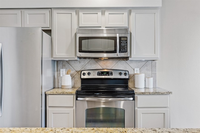 kitchen with tasteful backsplash, white cabinets, and appliances with stainless steel finishes