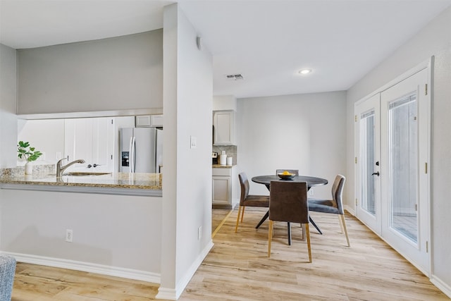 dining room featuring light hardwood / wood-style floors, sink, and french doors