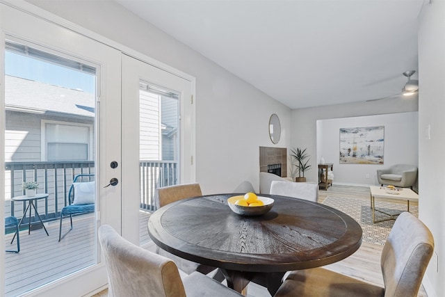 dining area with wood-type flooring and a tiled fireplace