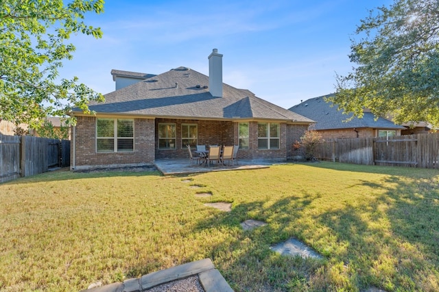 rear view of property with a lawn, a fenced backyard, brick siding, and a patio area