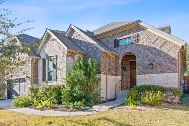 view of front of property featuring a front yard, brick siding, and stone siding