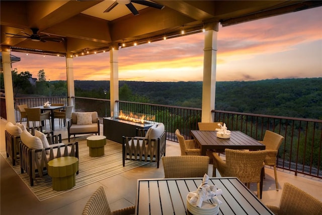 deck featuring ceiling fan, outdoor dining area, a view of trees, and an outdoor hangout area