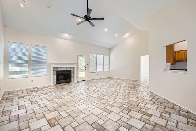 unfurnished living room with ceiling fan, high vaulted ceiling, and a tiled fireplace