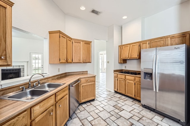 kitchen with a tile fireplace, appliances with stainless steel finishes, and sink