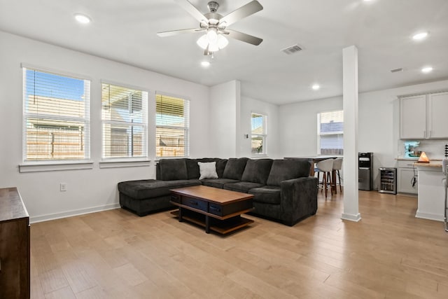 living room featuring plenty of natural light, ceiling fan, and light wood-type flooring