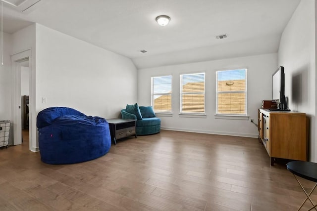 sitting room featuring baseboards, lofted ceiling, wood finished floors, and visible vents