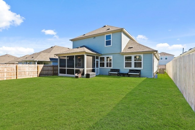rear view of property featuring a yard, a fenced backyard, and a sunroom