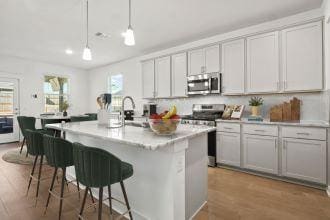 kitchen featuring a breakfast bar area, light countertops, appliances with stainless steel finishes, a sink, and wood finished floors