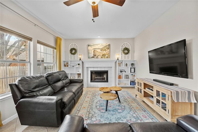 tiled living room featuring ceiling fan and a tiled fireplace