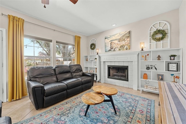 tiled living room with ceiling fan and a tiled fireplace