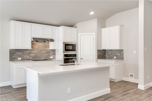 kitchen with white cabinets, ventilation hood, black appliances, and light hardwood / wood-style flooring