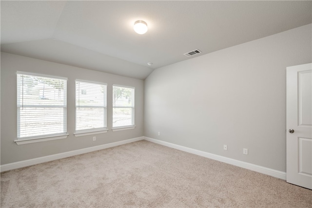 unfurnished room featuring light carpet, a healthy amount of sunlight, and vaulted ceiling