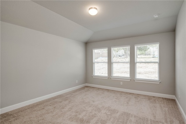 empty room with plenty of natural light, lofted ceiling, and light carpet