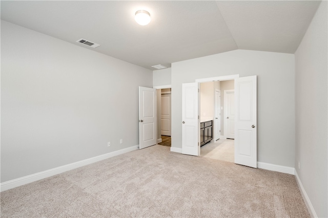 unfurnished bedroom featuring light carpet and vaulted ceiling