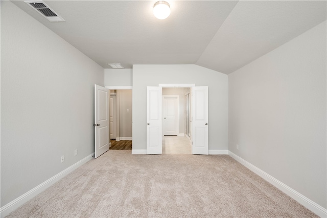 unfurnished bedroom featuring light colored carpet and lofted ceiling