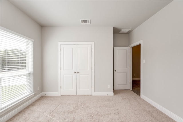 unfurnished bedroom with a closet and light colored carpet