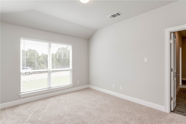 carpeted spare room with vaulted ceiling