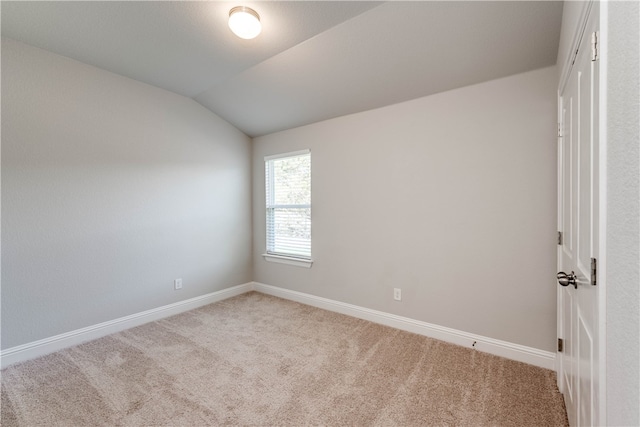 spare room featuring carpet flooring and vaulted ceiling