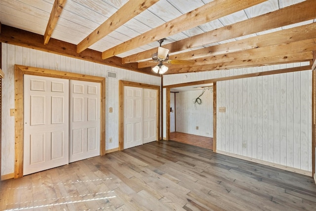 unfurnished bedroom featuring ceiling fan, wooden ceiling, beamed ceiling, wood walls, and hardwood / wood-style flooring