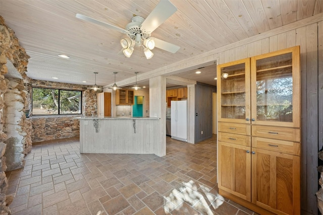 kitchen with hanging light fixtures, white fridge, a breakfast bar area, wooden walls, and wood ceiling