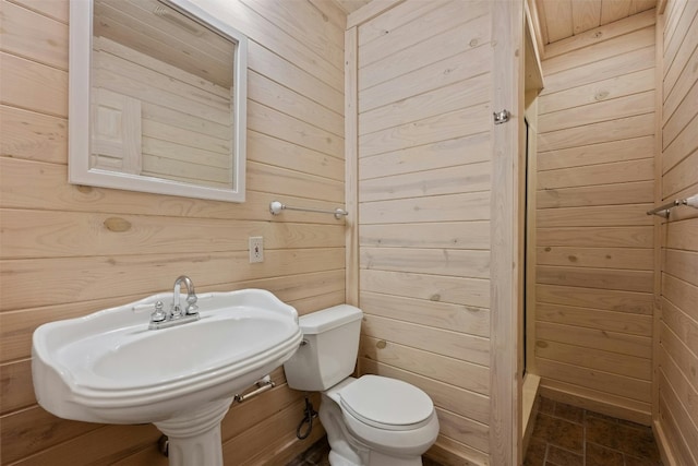 bathroom with sink, toilet, and wood walls