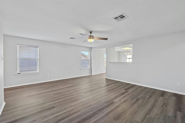 unfurnished room featuring dark wood-style floors, visible vents, baseboards, and a ceiling fan