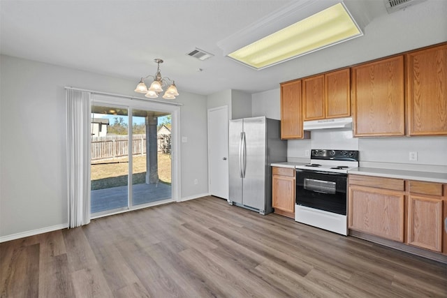 kitchen with white electric range oven, light countertops, hanging light fixtures, freestanding refrigerator, and under cabinet range hood