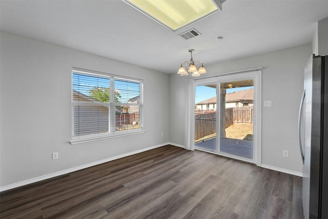 unfurnished dining area with a healthy amount of sunlight, an inviting chandelier, baseboards, and dark wood finished floors