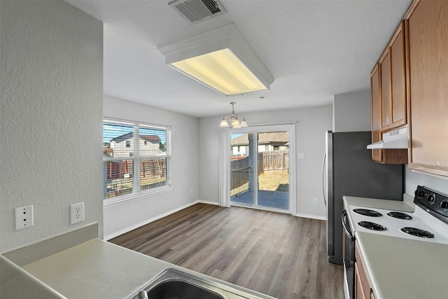 kitchen featuring pendant lighting, range with electric stovetop, light countertops, visible vents, and under cabinet range hood