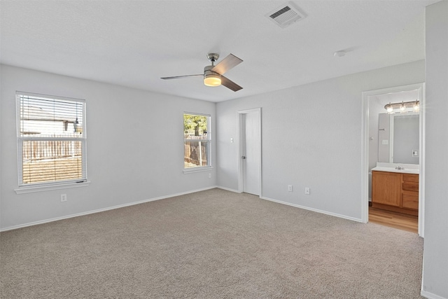 unfurnished bedroom featuring baseboards, ceiling fan, visible vents, and light colored carpet