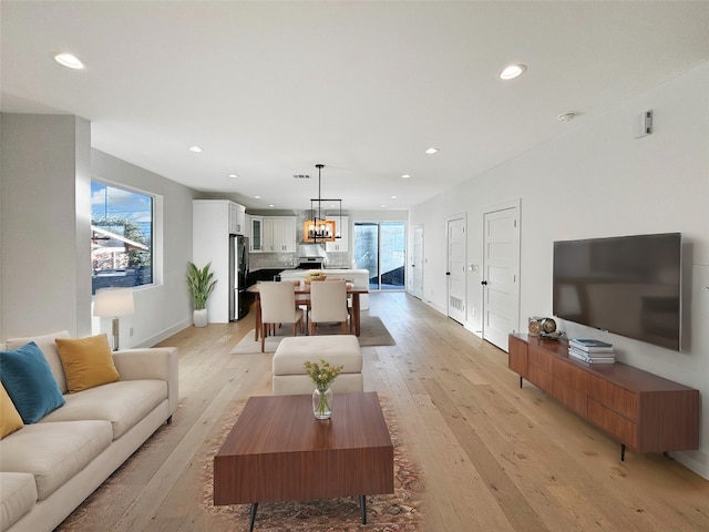 living room featuring light wood-type flooring, a wealth of natural light, and an inviting chandelier