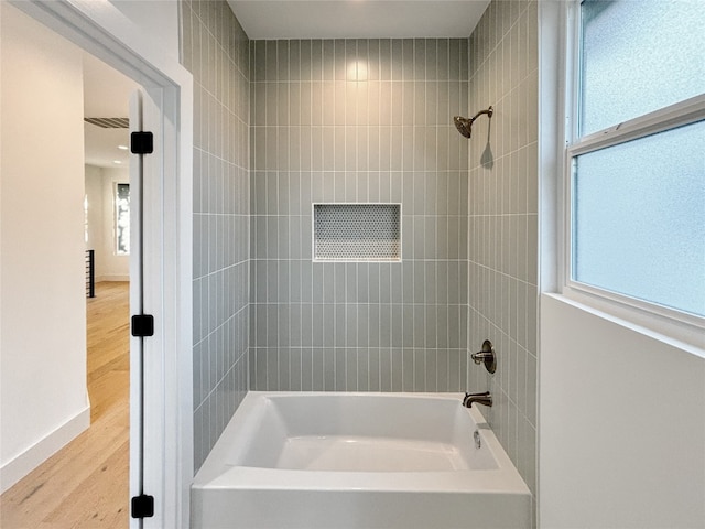 bathroom with hardwood / wood-style flooring and tiled shower / bath