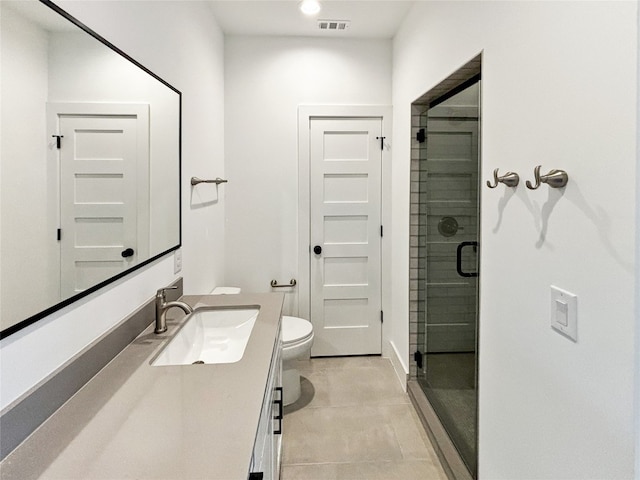 bathroom featuring tile patterned floors, vanity, toilet, and a shower with shower door