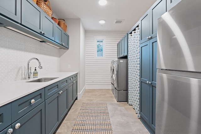 clothes washing area featuring sink, washing machine and dryer, and cabinets