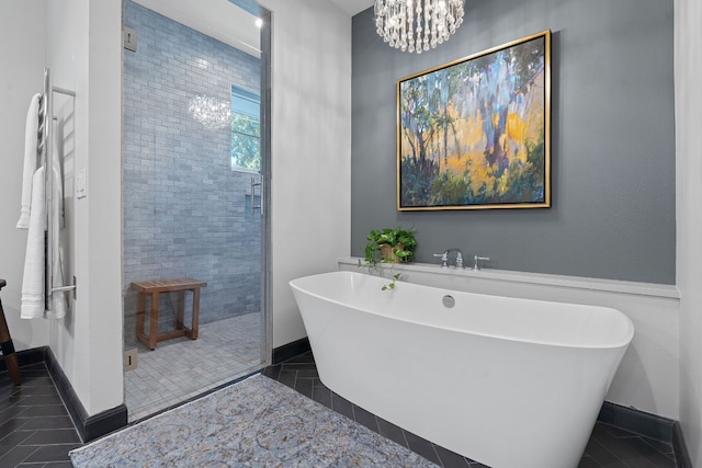 bathroom with plus walk in shower, a notable chandelier, and tile patterned floors