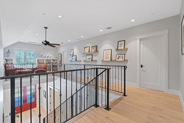 corridor with lofted ceiling and light hardwood / wood-style floors