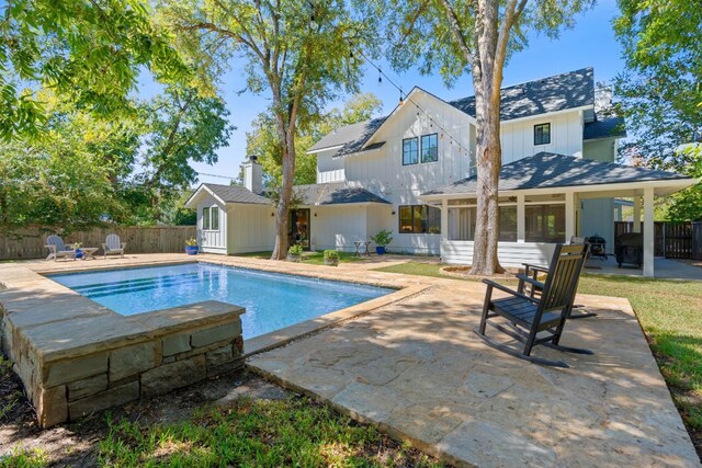 view of swimming pool featuring a sunroom, a patio area, and a shed