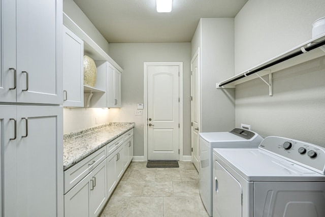 laundry area featuring washer and clothes dryer, light tile patterned flooring, and cabinets