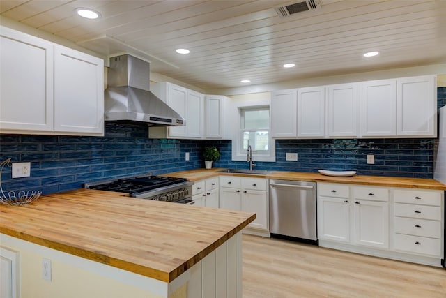 kitchen with white cabinets, stainless steel appliances, butcher block counters, and wall chimney range hood