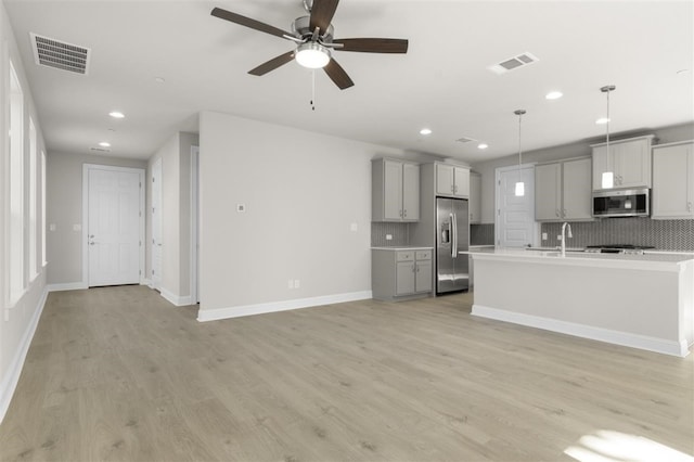 kitchen featuring gray cabinetry, stainless steel appliances, light hardwood / wood-style flooring, decorative light fixtures, and decorative backsplash