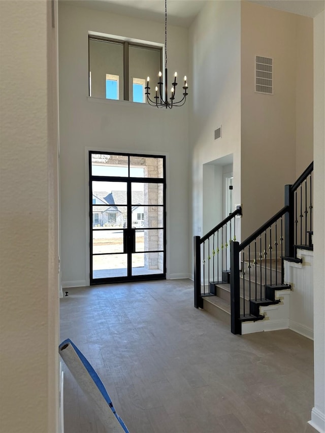 foyer entrance with a towering ceiling, french doors, and a chandelier