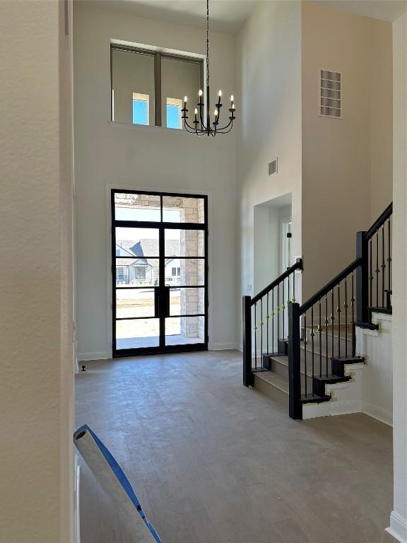 foyer with a chandelier, stairway, a towering ceiling, and visible vents