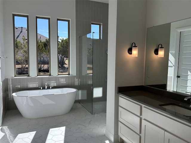 full bathroom featuring tiled shower, tile patterned floors, a freestanding bath, vanity, and tile walls