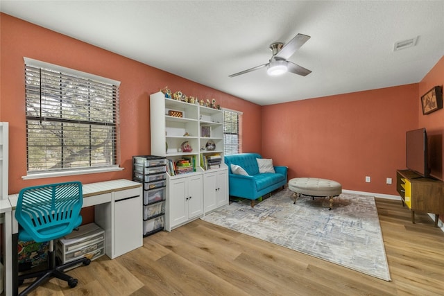 office with a textured ceiling, light hardwood / wood-style floors, a wealth of natural light, and ceiling fan